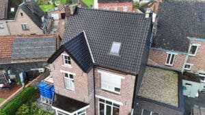 Plat dak met grindbedekking naast een woning met leien gevelbekleding